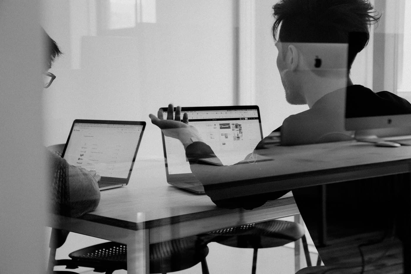 Two people talking through work across their laptops
